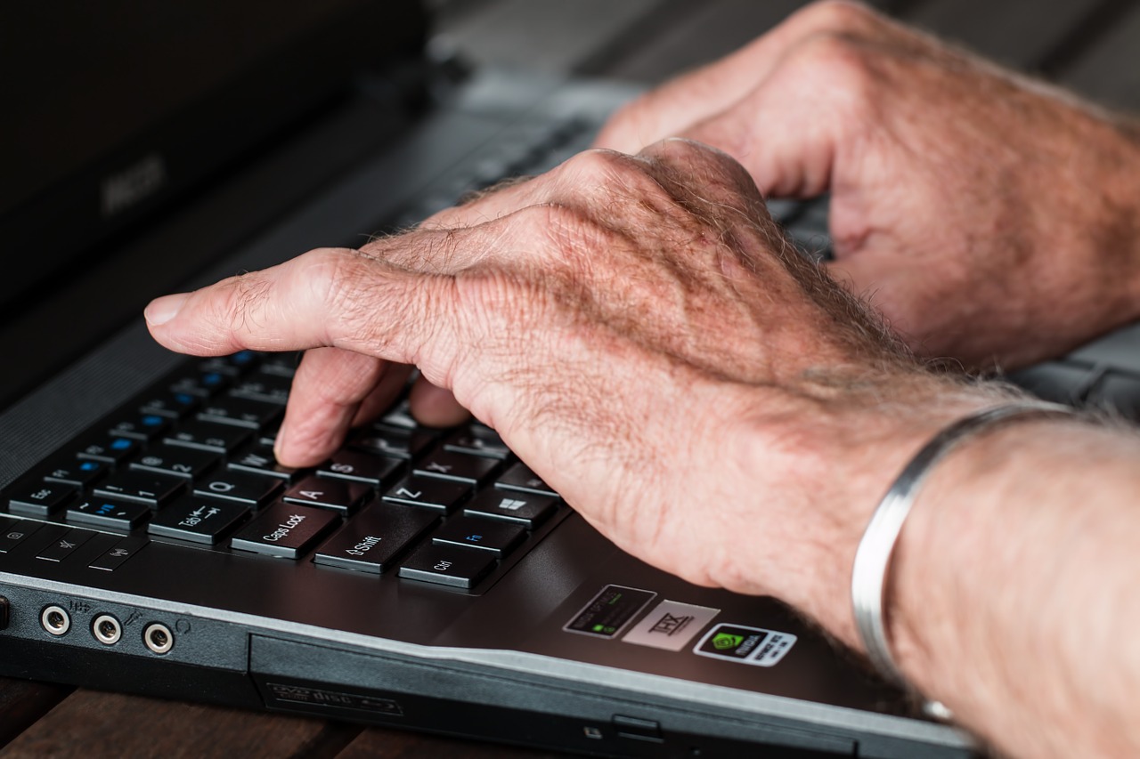 Arthritic hands typing on a keyboard.