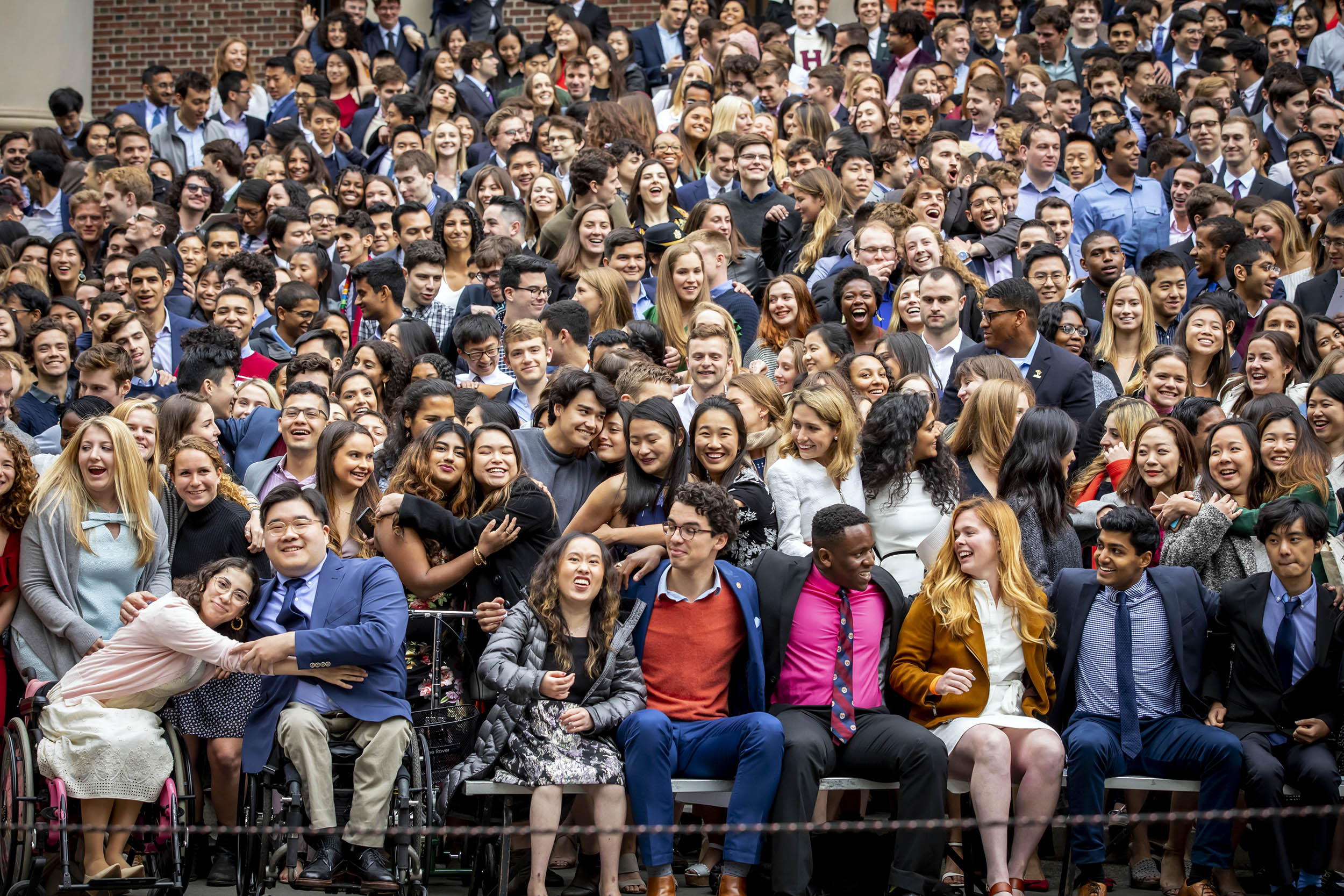 Seniors smile and hug on the steps of Widener Library.