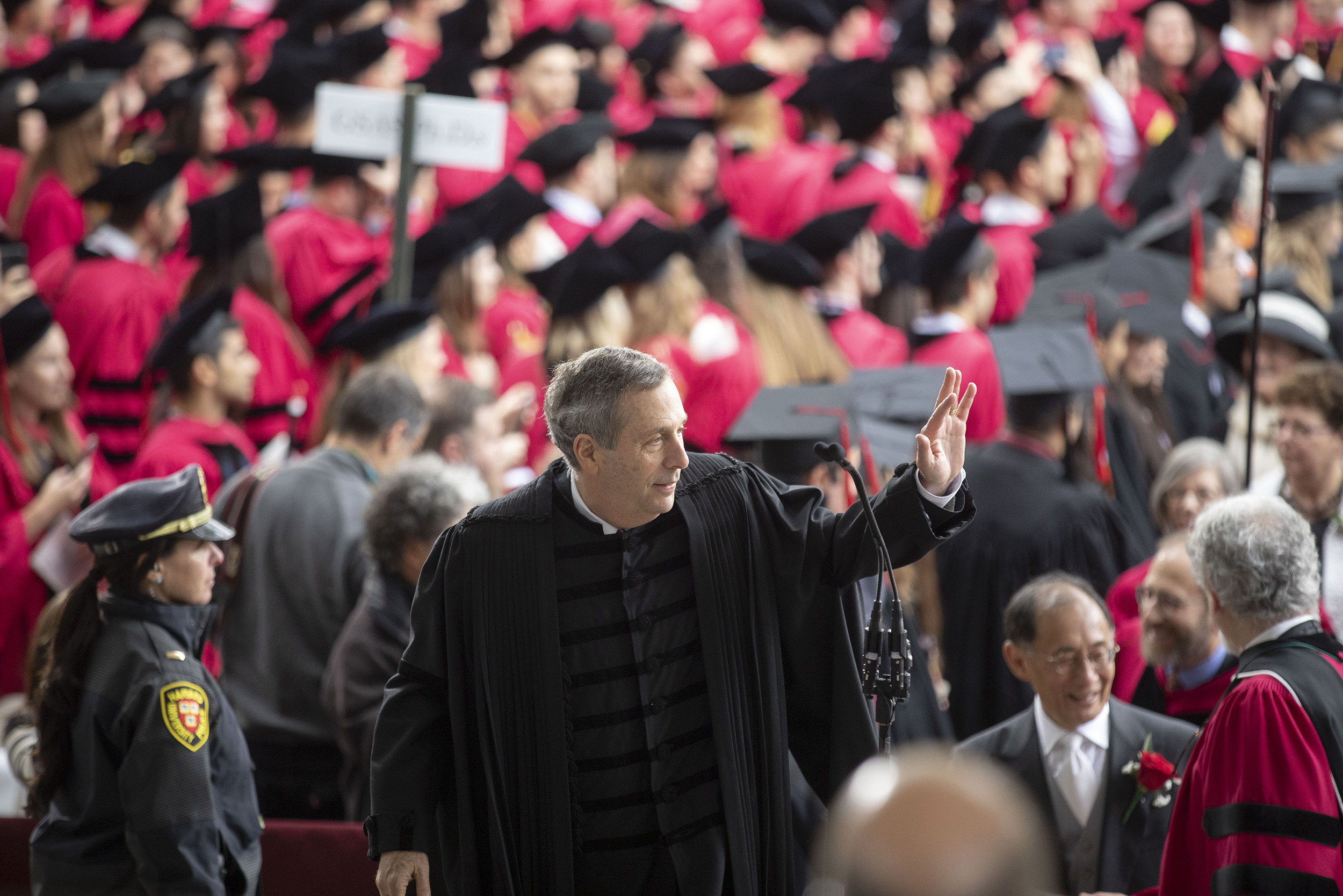 Larry Bacow waves from the stage.