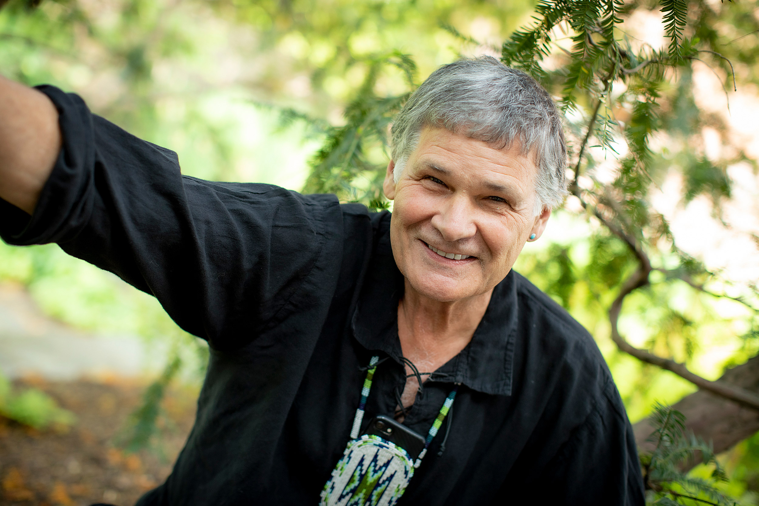 Portrait of Dennis Norman outside, framed by a tree