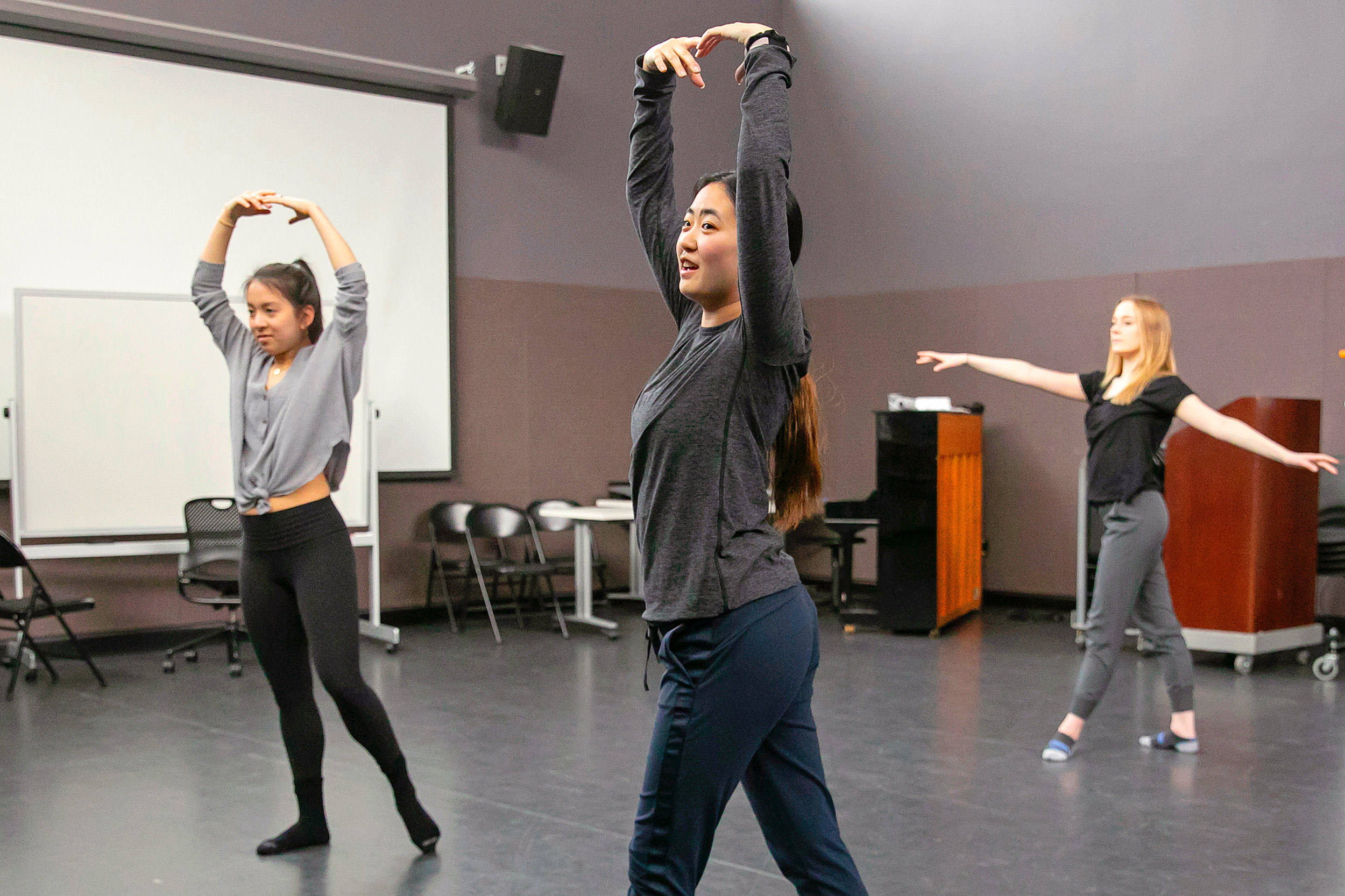 Three dancers pose with arms outstretched.