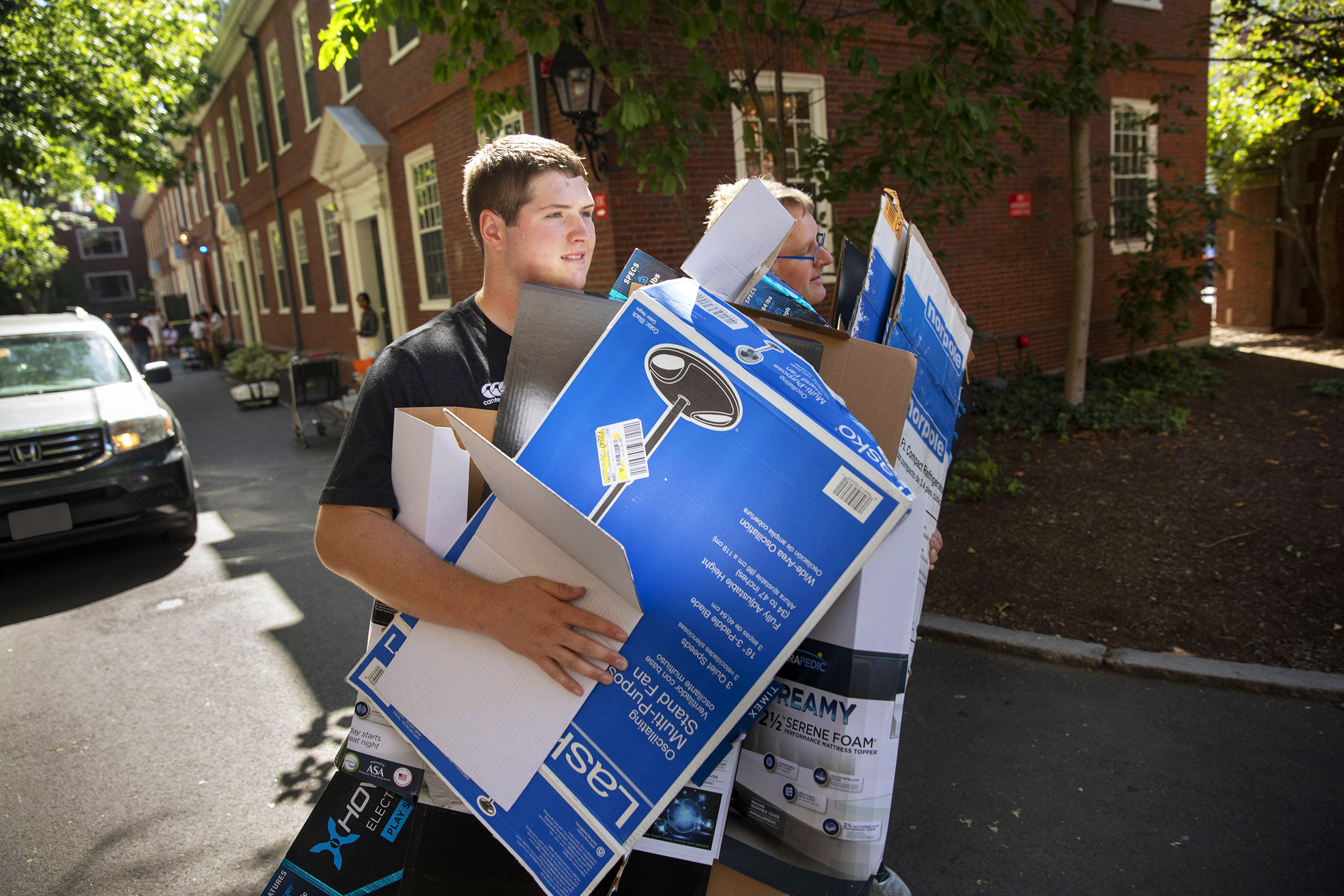 Student carrying boxes with his father