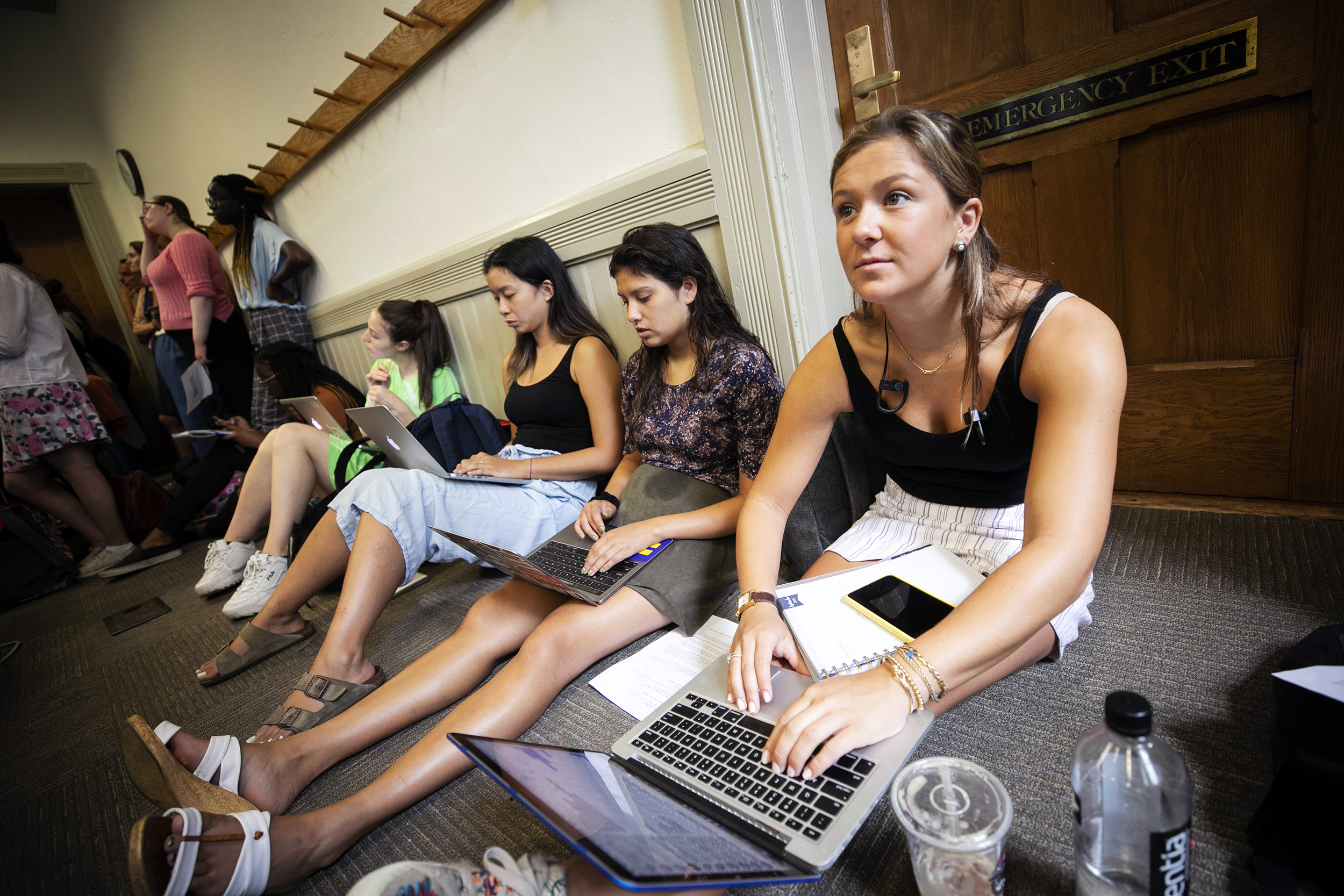 Students sit on floor listening to lecture.