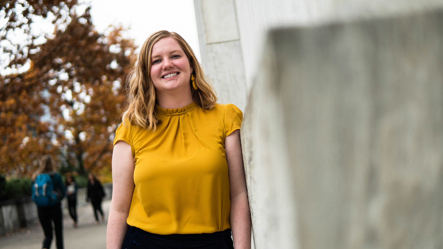 Kalya leaning against a building on campus