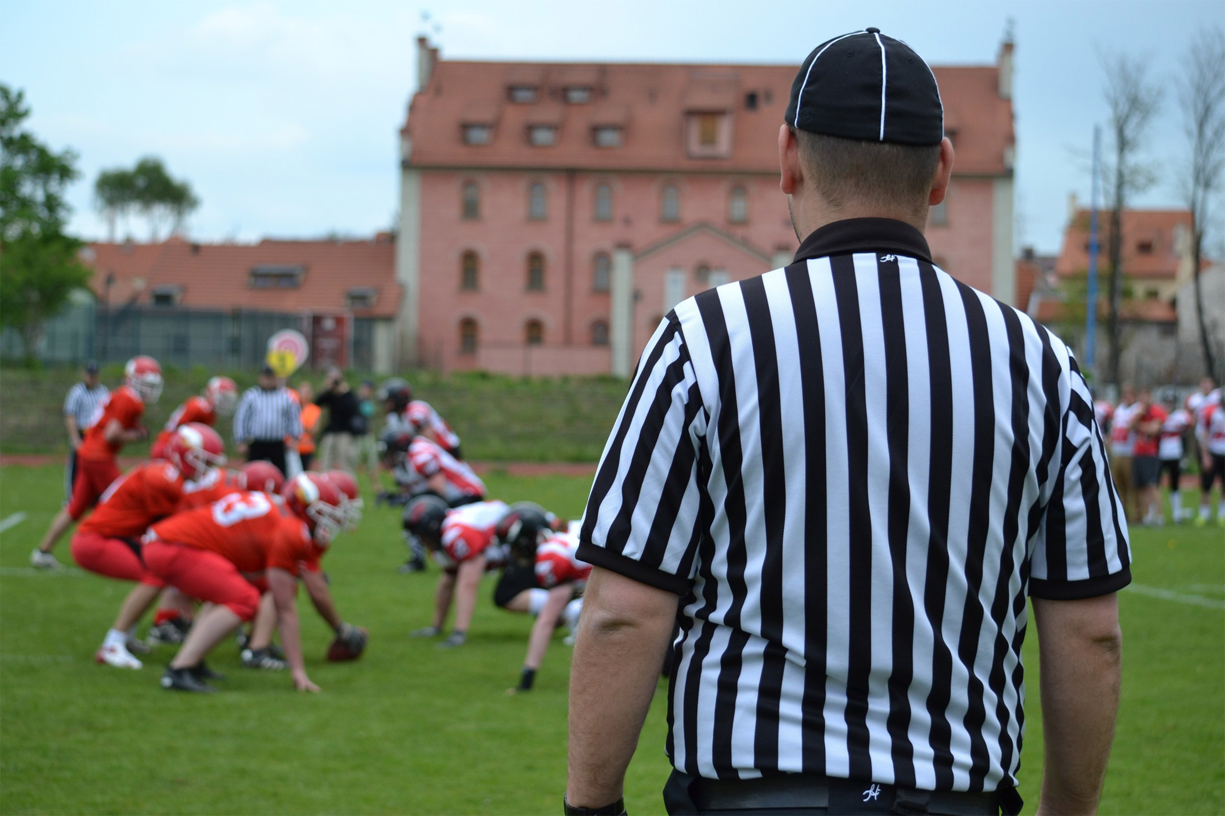 Referee on field with children playing sports.