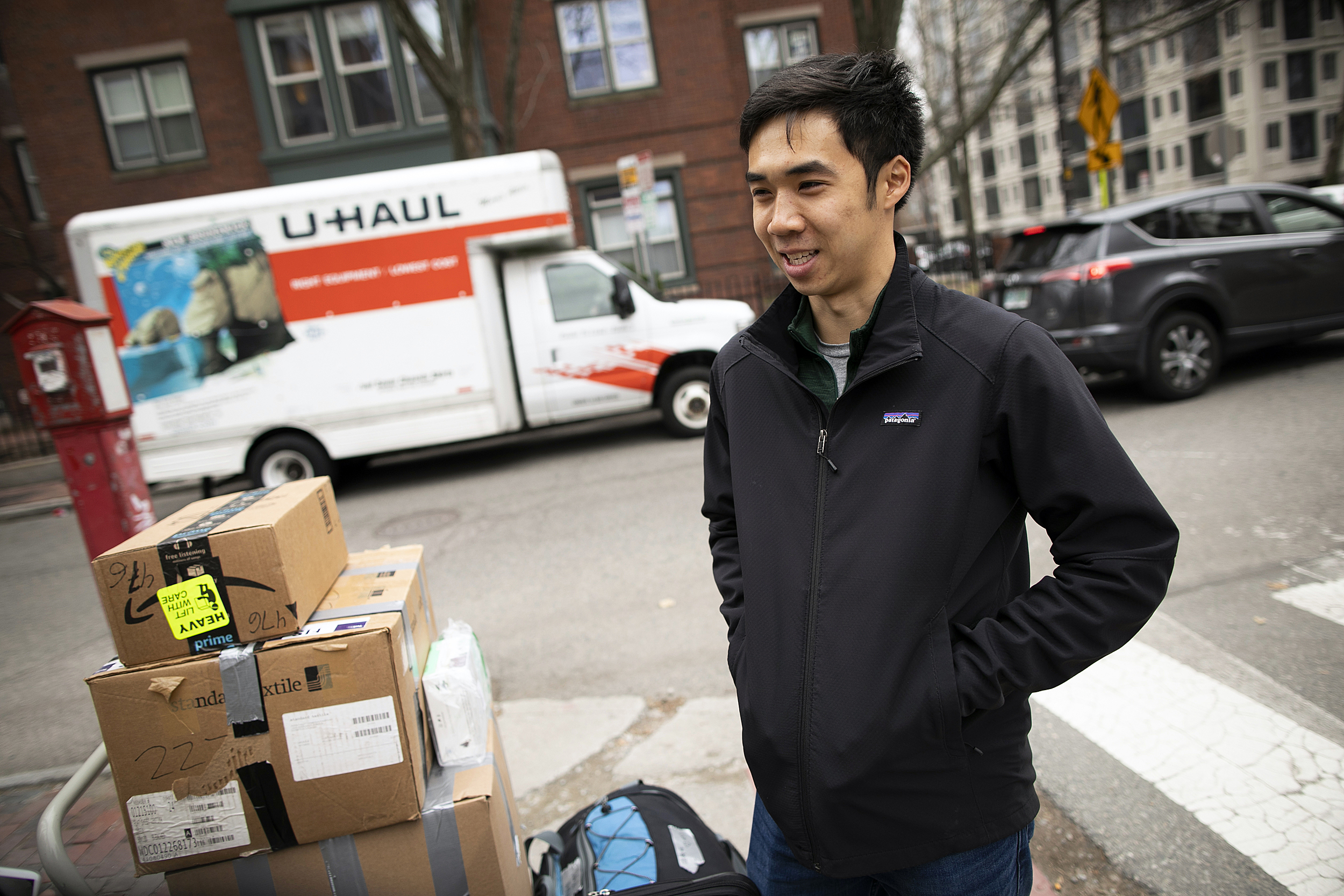 Victor Qin stands with boxes by a moving truck.