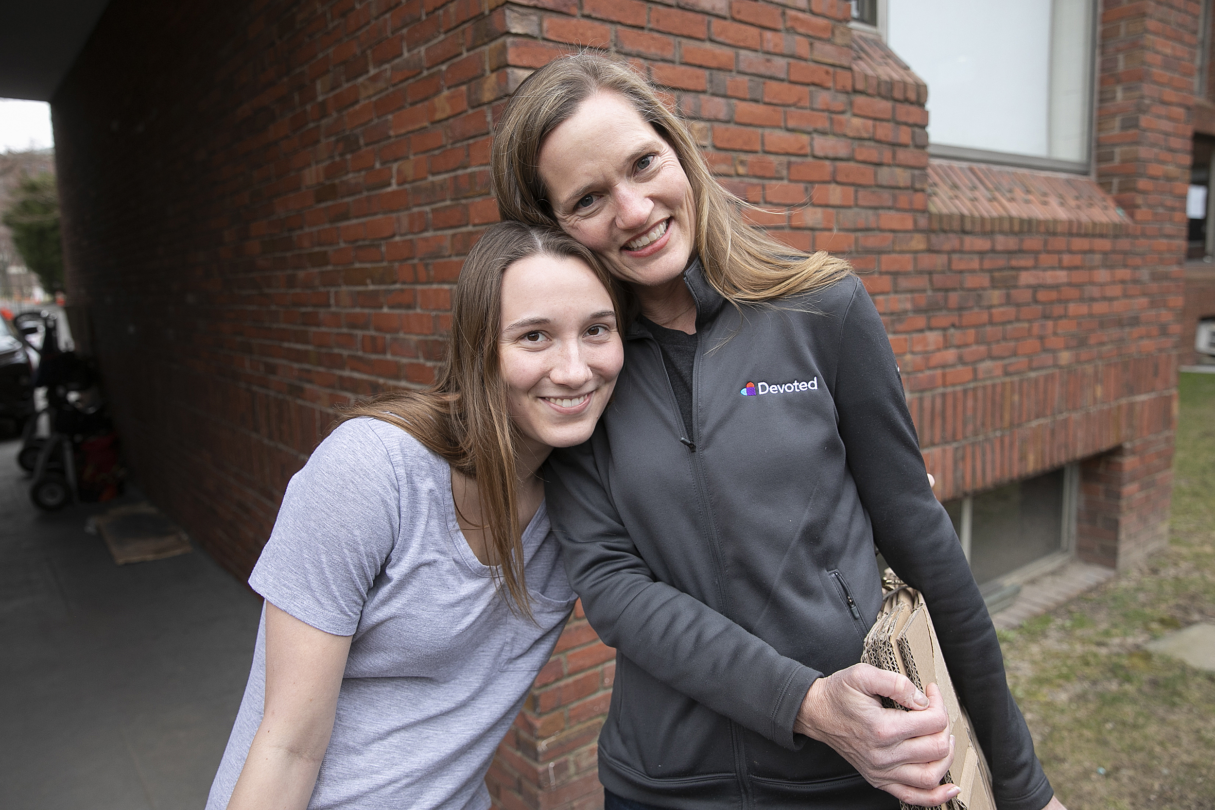 Hannah Thurlby and Leslie Brunner carry unassembled cardboard boxes.