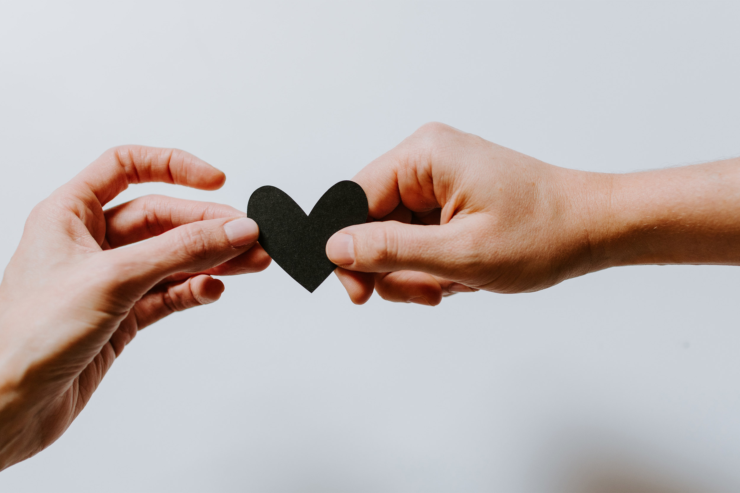 Two hands holding a single paper heart.