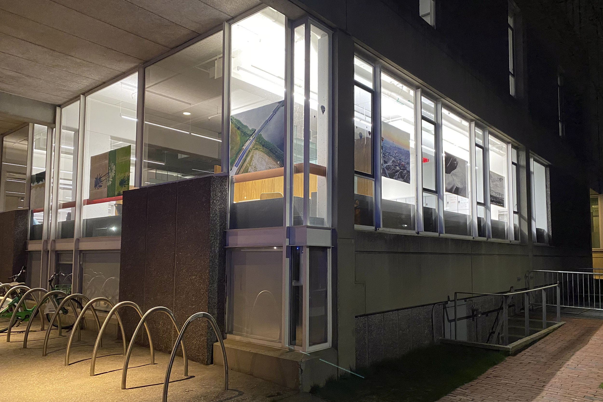 Art in windows of Cabot Library, lit up at night.