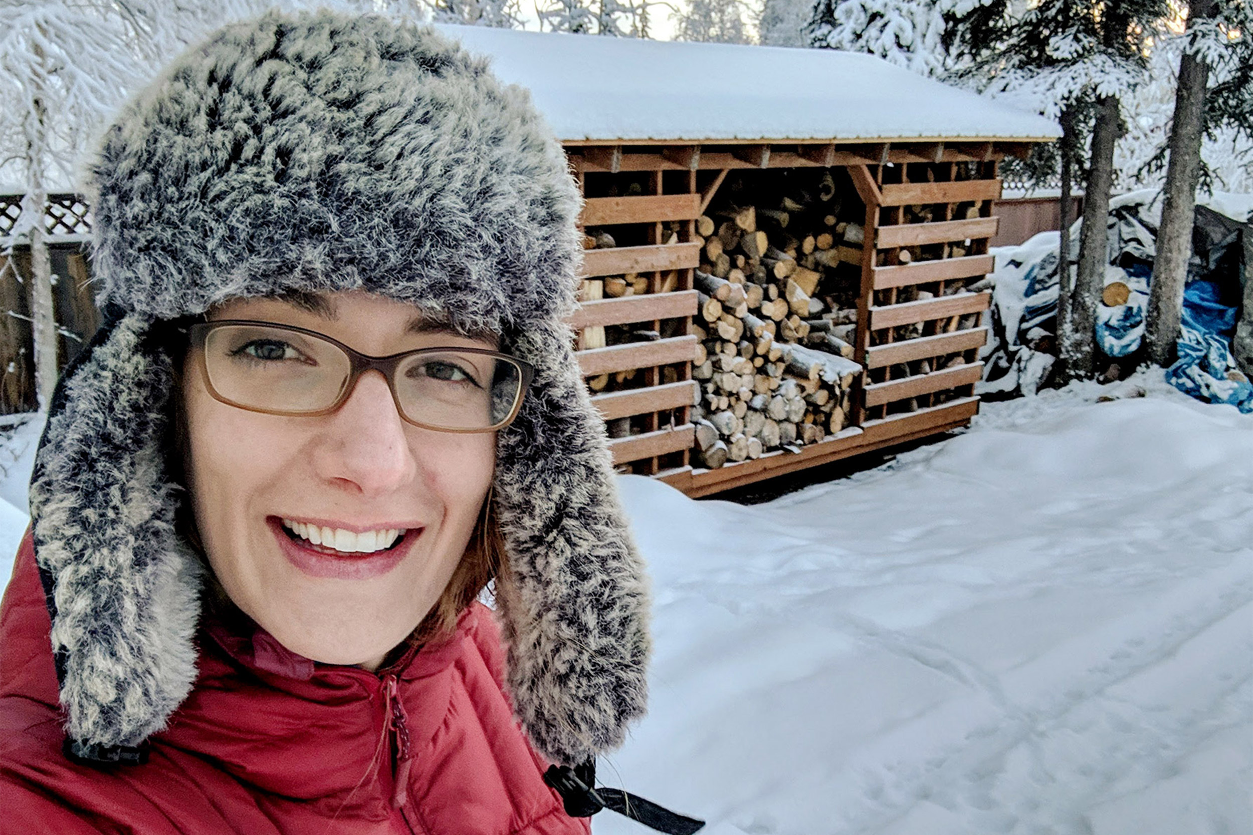 Alicia Nelson, M.P.H. ’20 in front of woodpile.