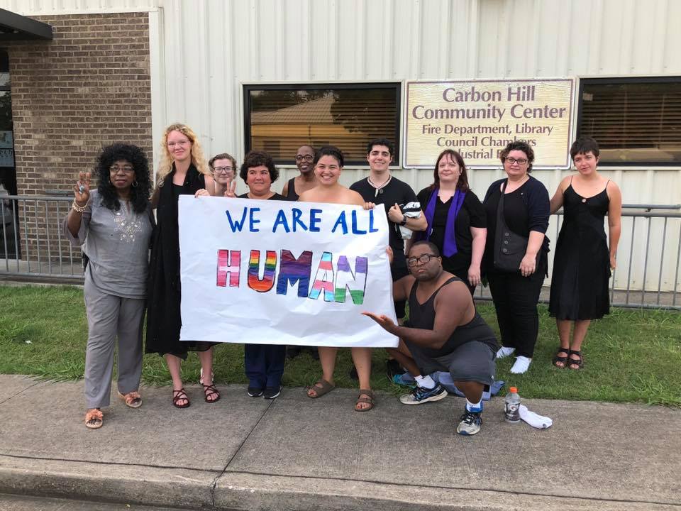 A group of people holding a sign that says "We are all human"