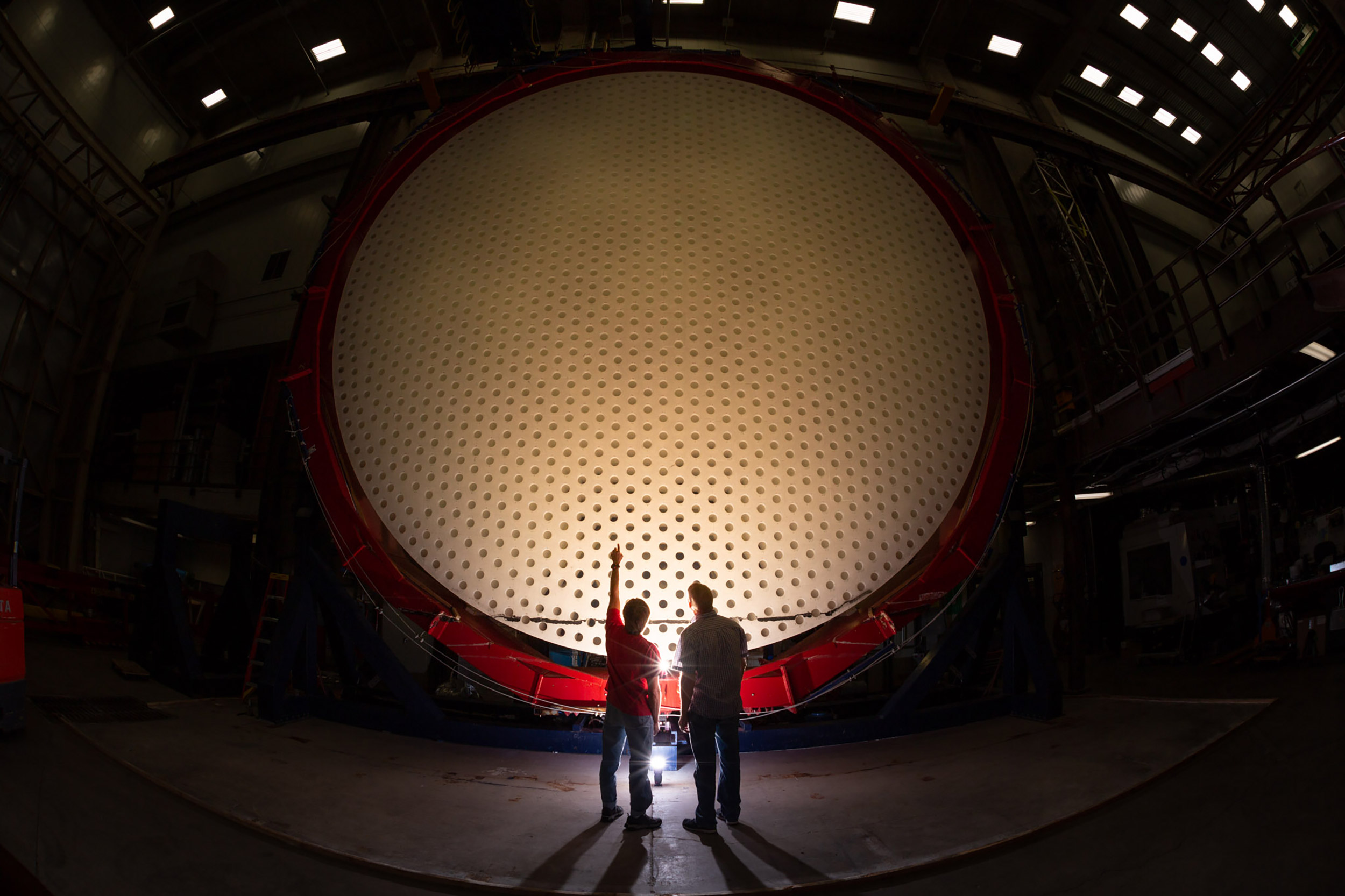 Two individuals stand in front of Magellan Mirror.