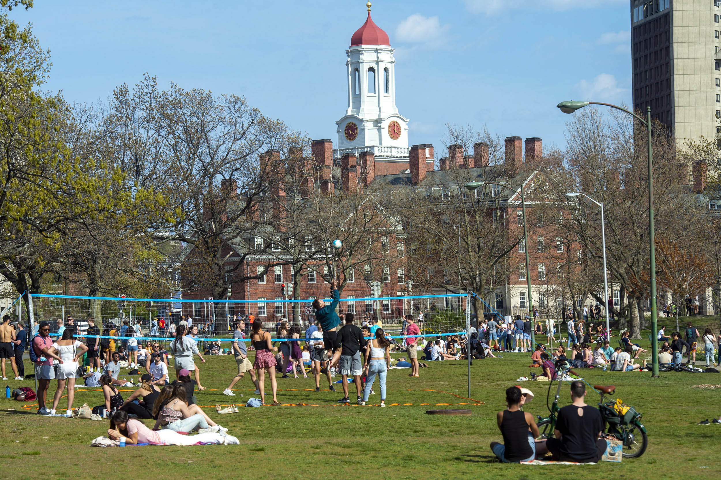 Members of the Cambridge community gather on the lawn by the Weeks Footbridge along Memorial Drive.