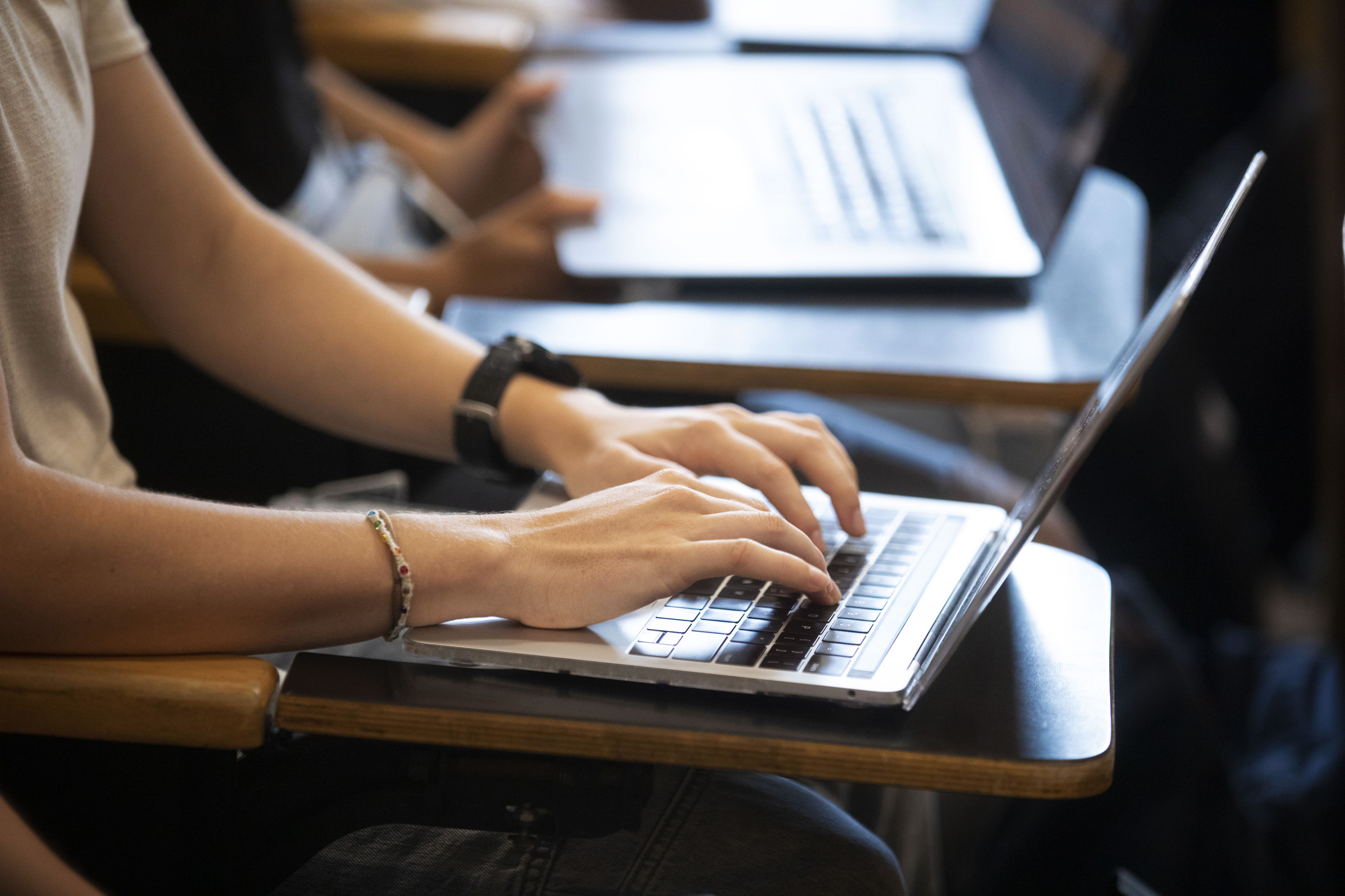 Students type notes on their laptop computers.