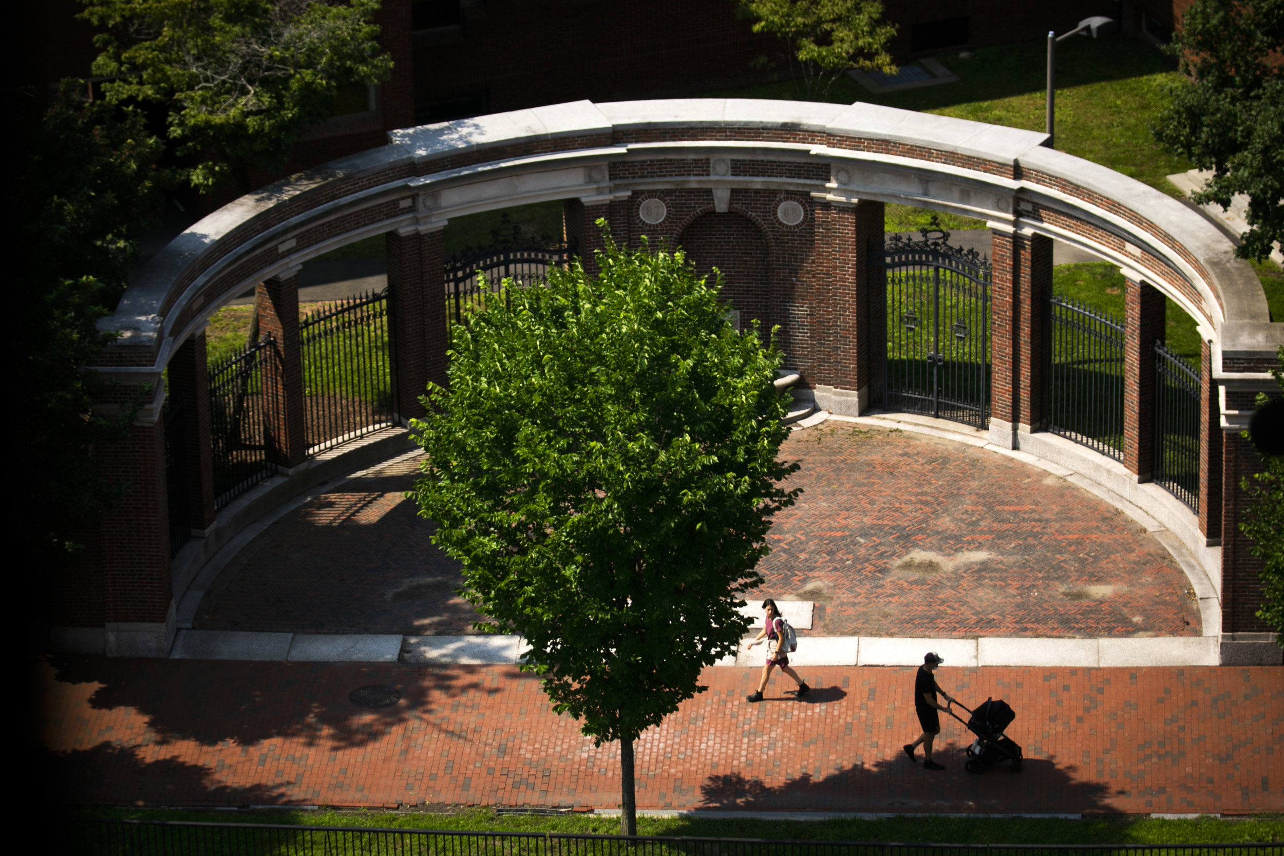 Pedestrians pass alongside the gates of Harvard Yard.