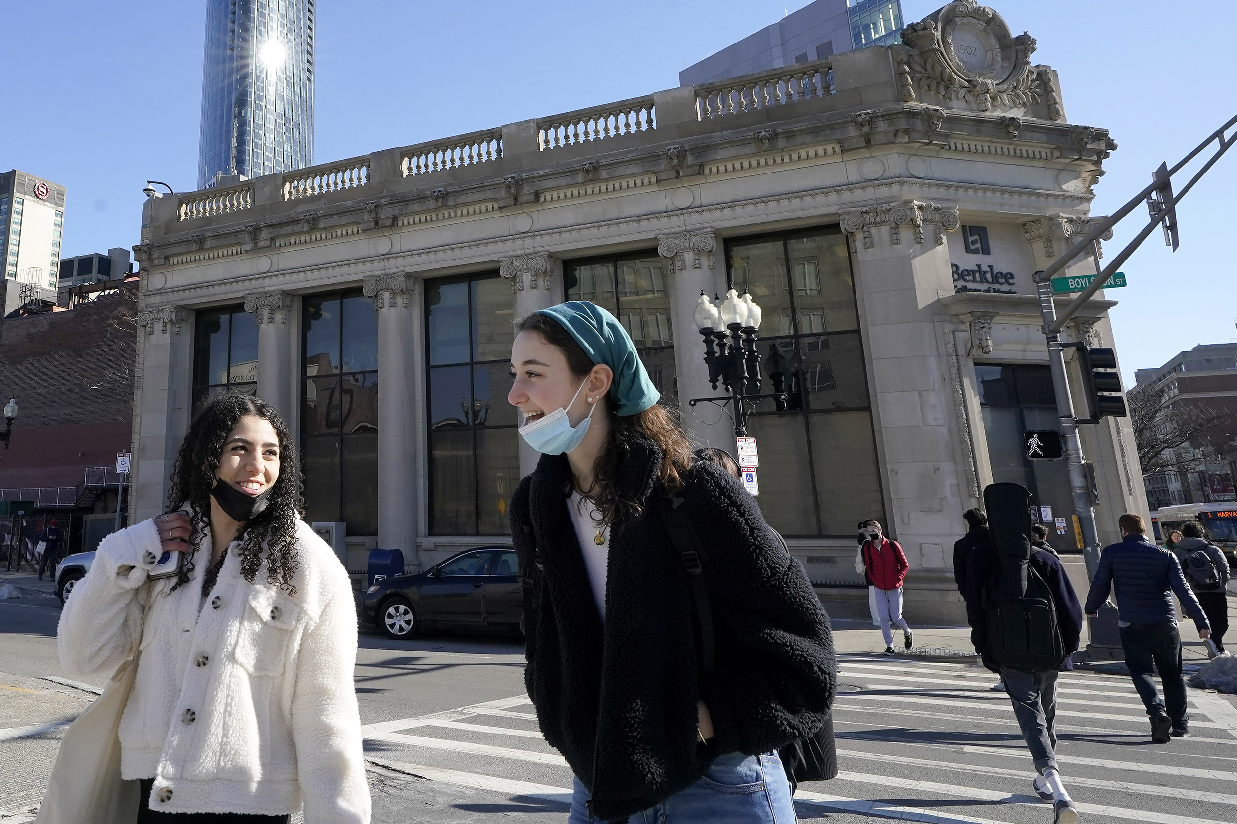 Pedestrians in Boston chat as they cross street with masks lowered.