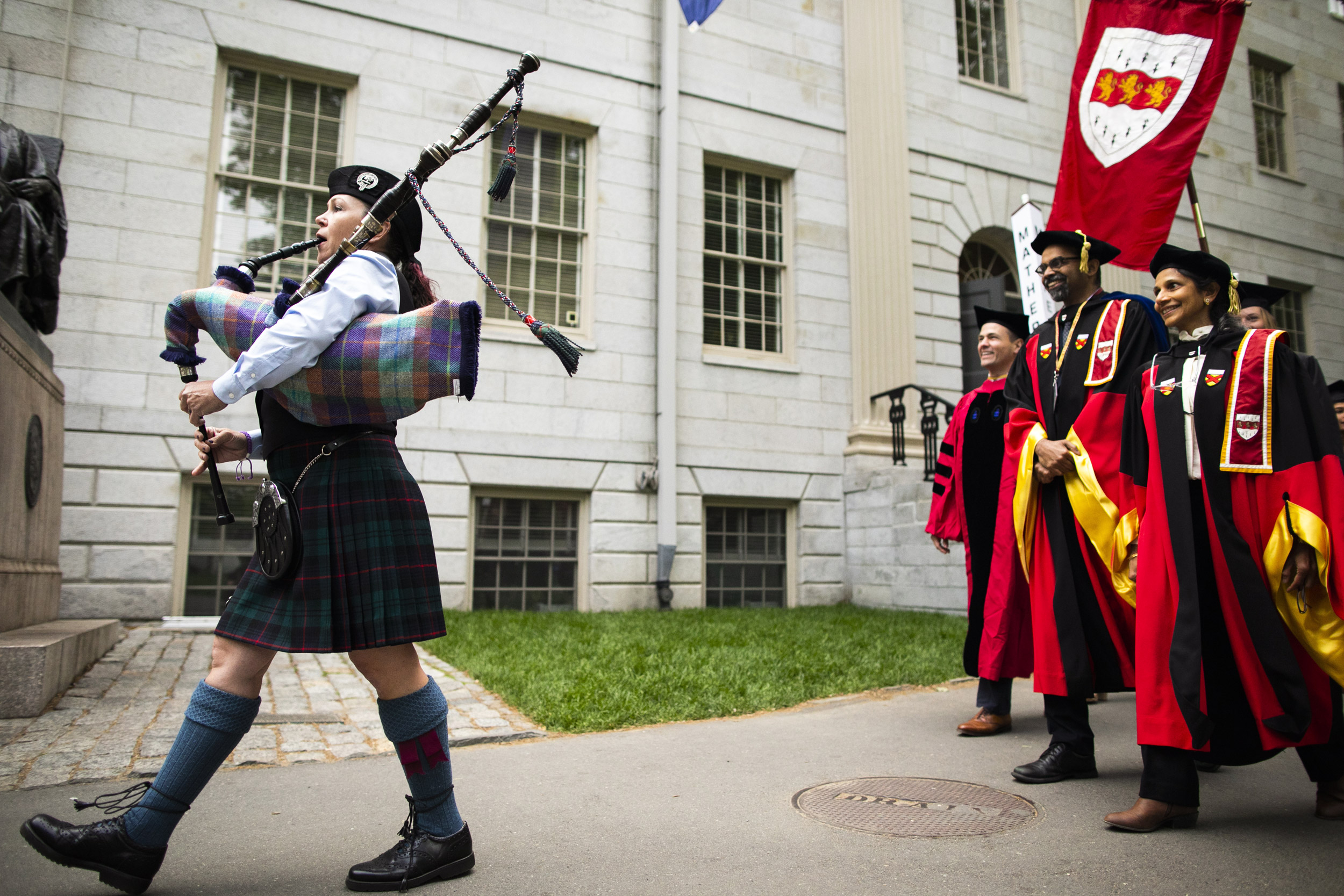 A bagpiper processes through Harvard Yard.