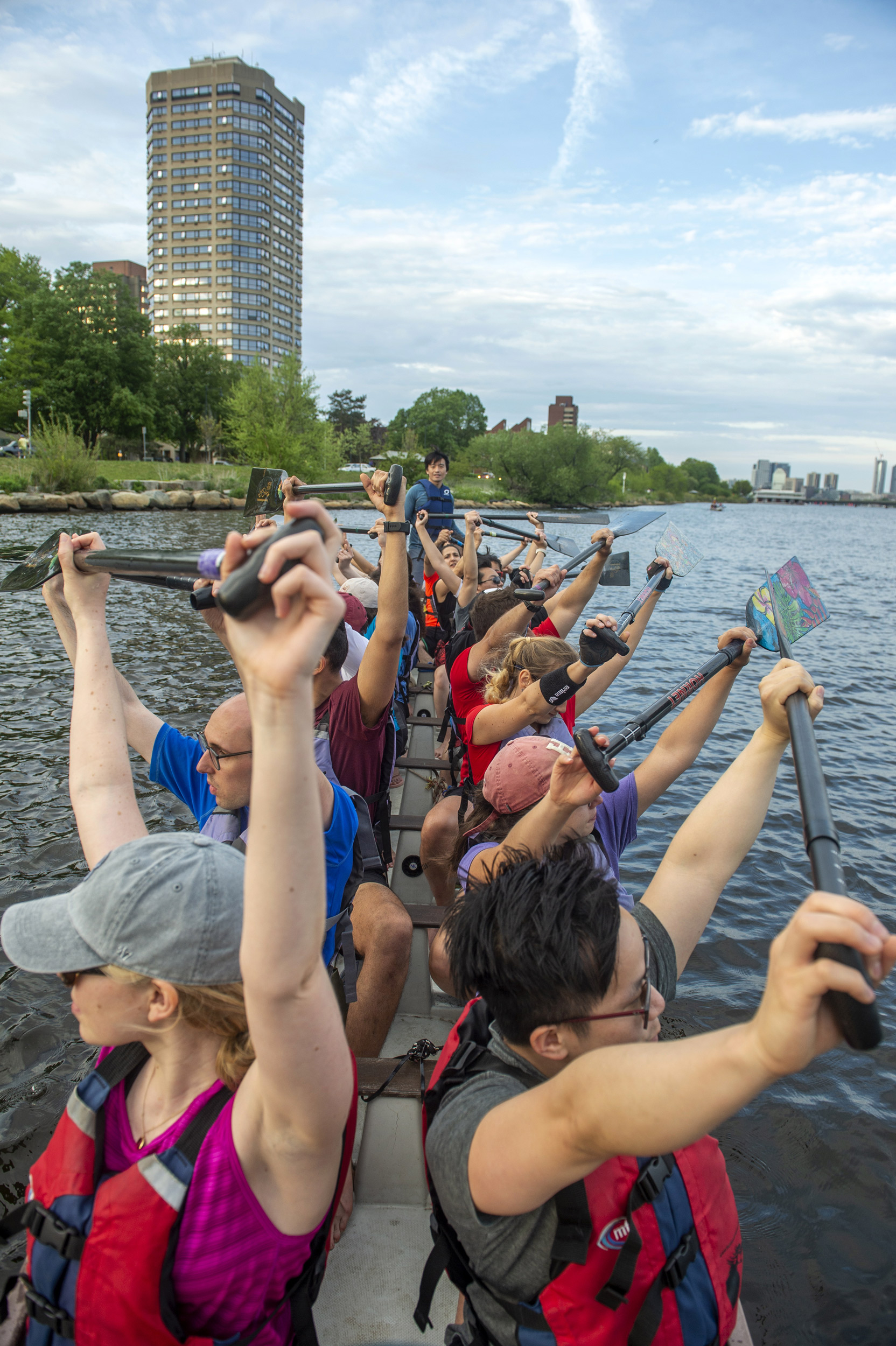 Crew members raise their paddles above their heads.