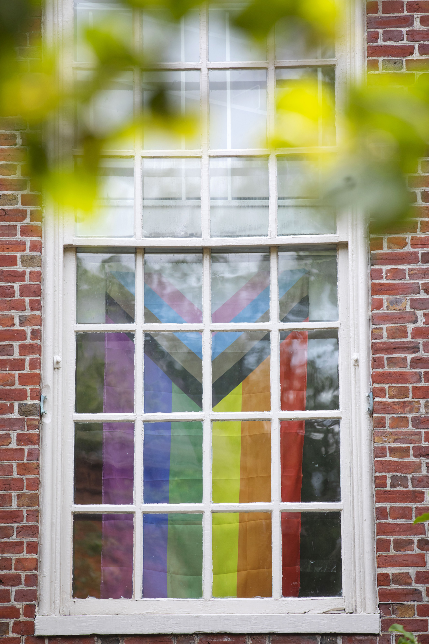 The Pride Flag is displayed in a bay window at Lehman Hall.