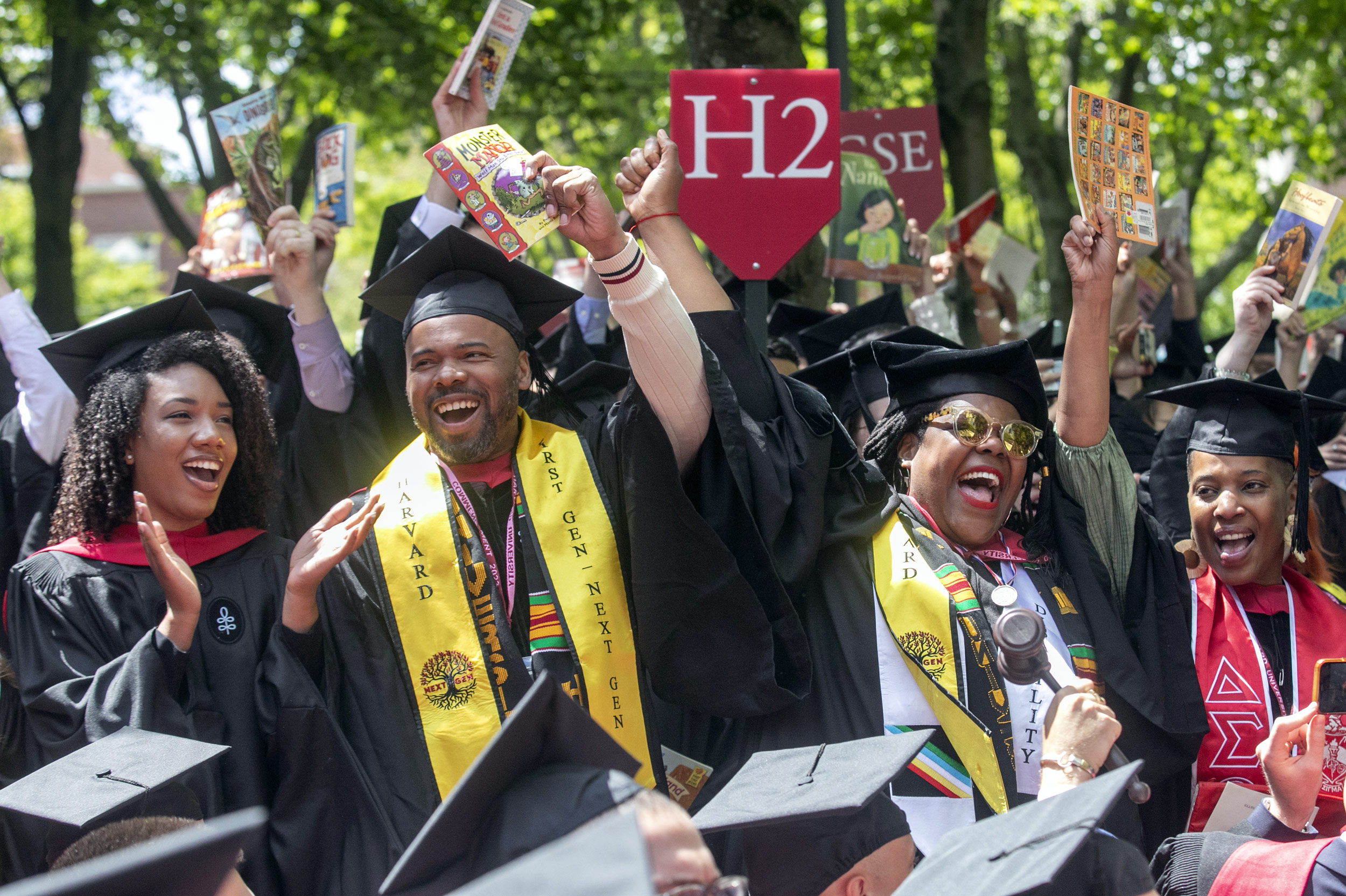 Graduates from School of Education wave children's books.