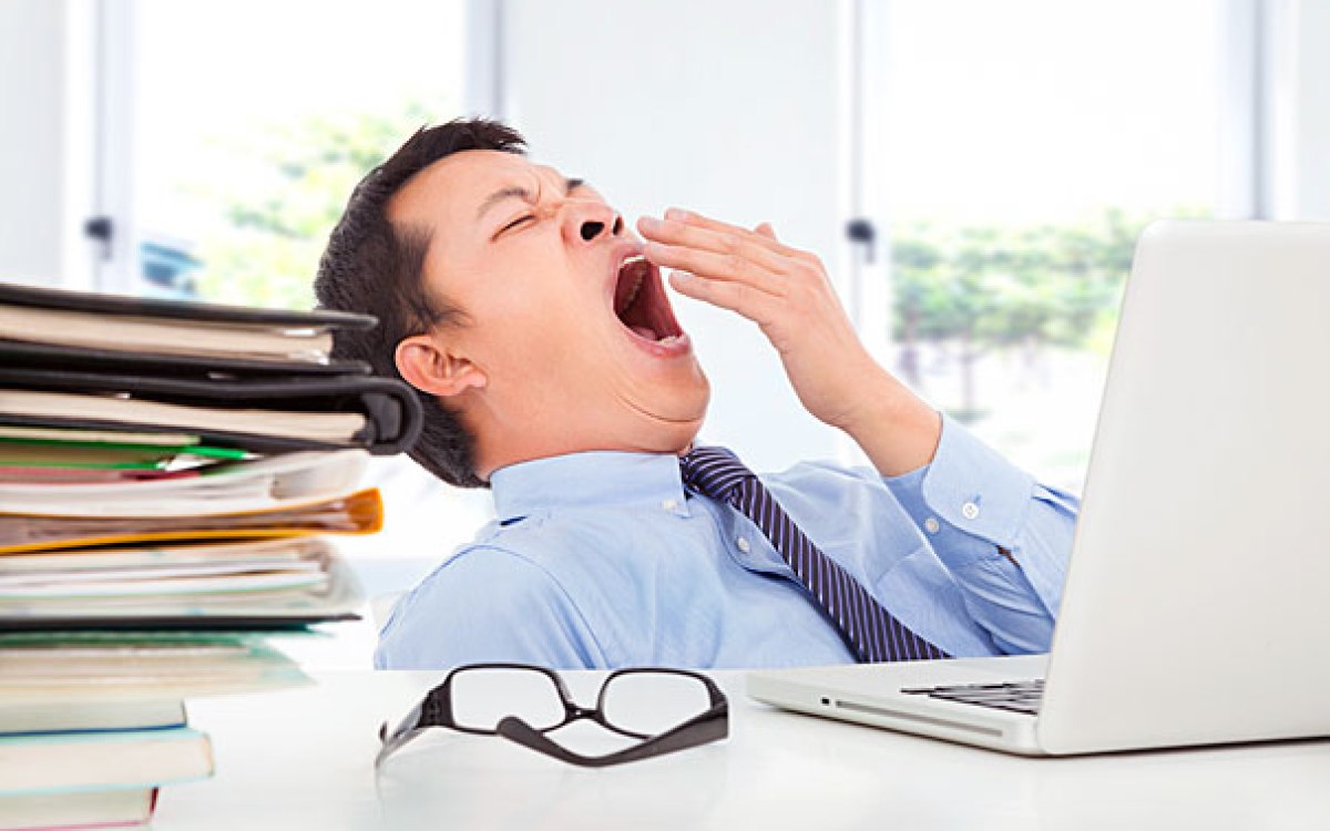 Exhausted young businessman yawning at work in office