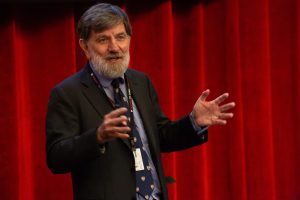 Man giving speech in front of curtain