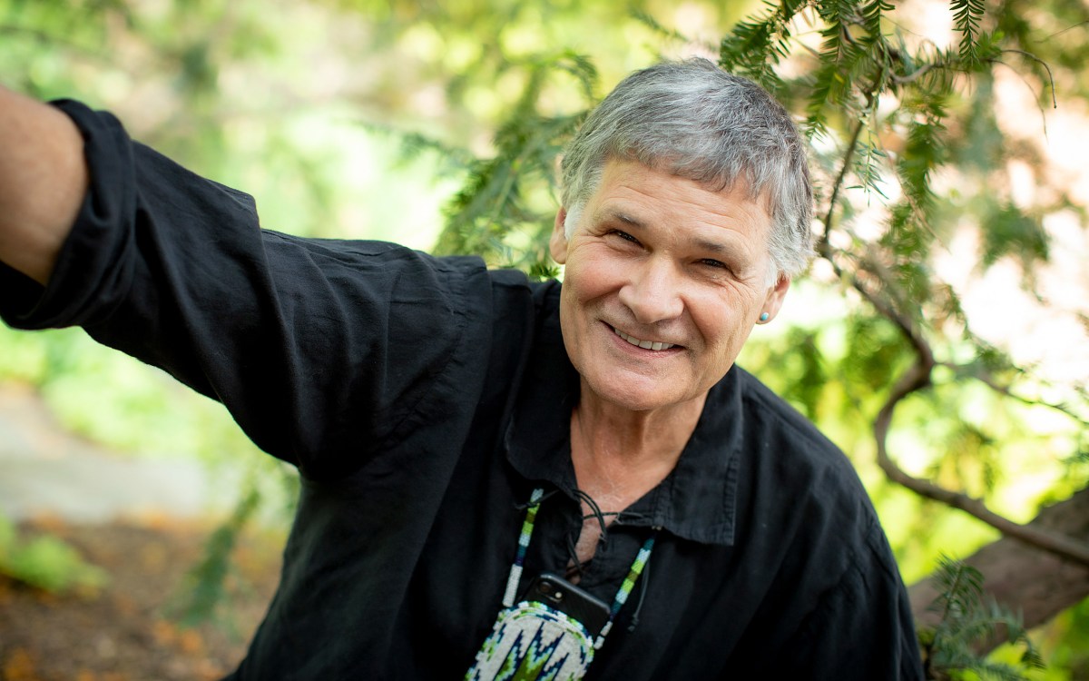 Portrait of Dennis Norman outside, framed by a tree