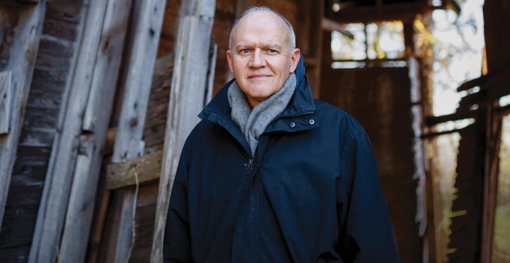 Jim in front of a barn with a jacket on