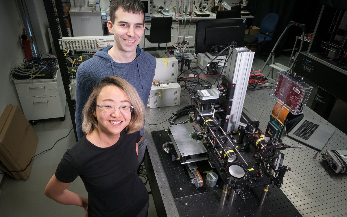 Two researchers in a lab with a large microscope.