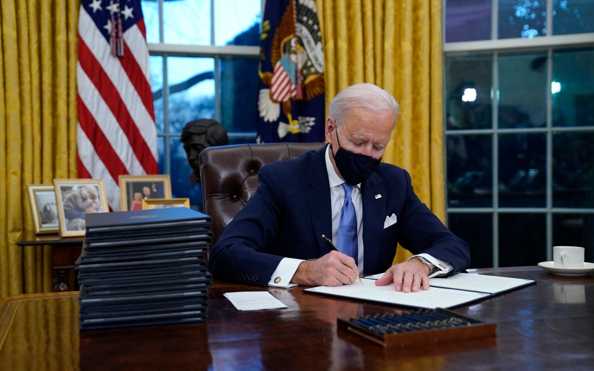 Joe Biden signs his first executive orders in the Oval Office.