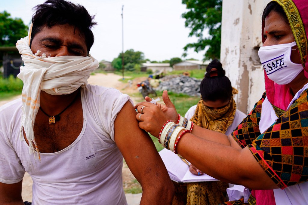 India worker giving vaccines door to door.