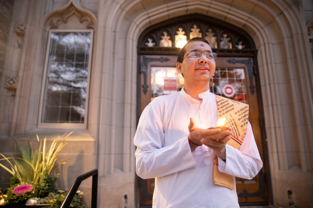 (Venerable) Vandan Sadhak, HDS student and Hindu monastic celebrates Diwali at dusk outside Swartz Hall.