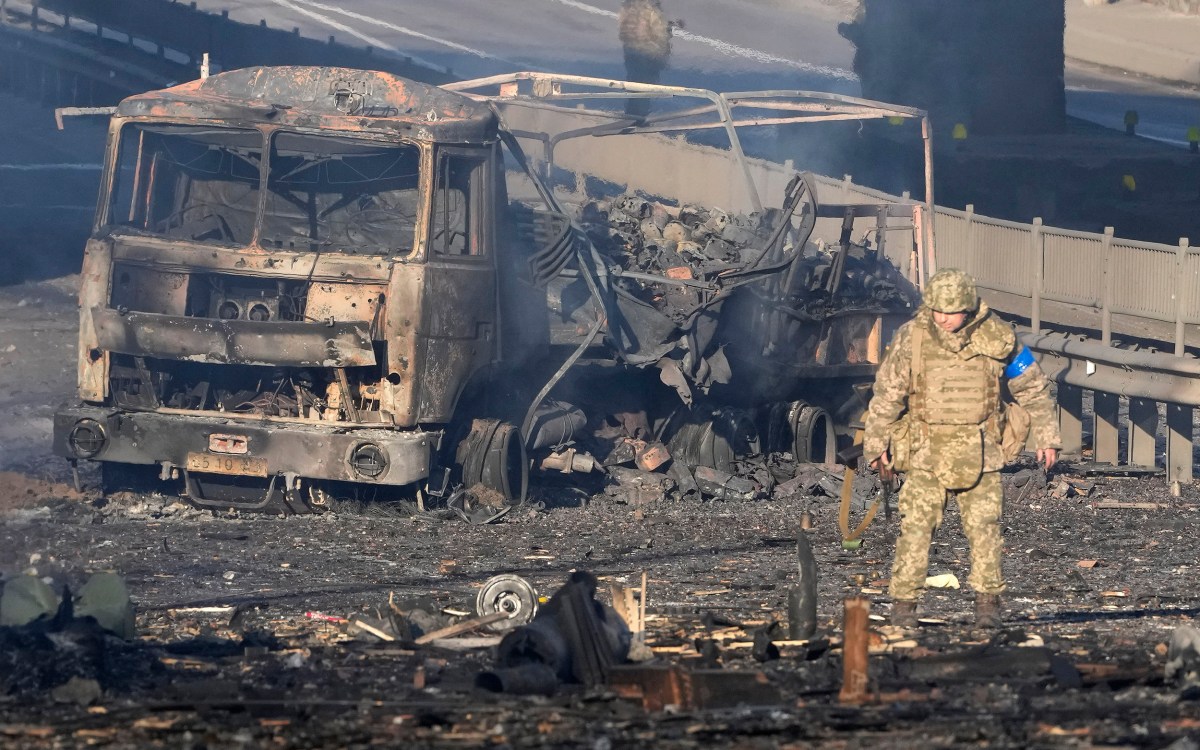 Soldier passes military truck burning in Kyiv, Ukraine.