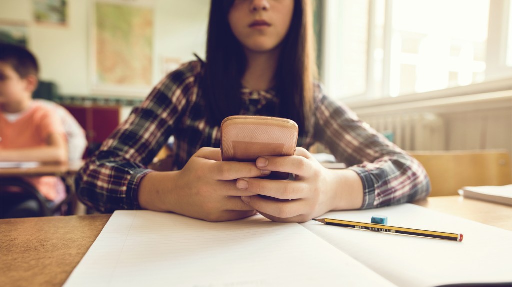 Close up of elementary student typing text message on smart phone