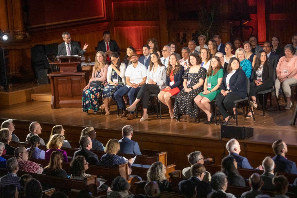 Larry Bacow speaks during Harvard Heroes ceremony on stage alongside fellow recipients.