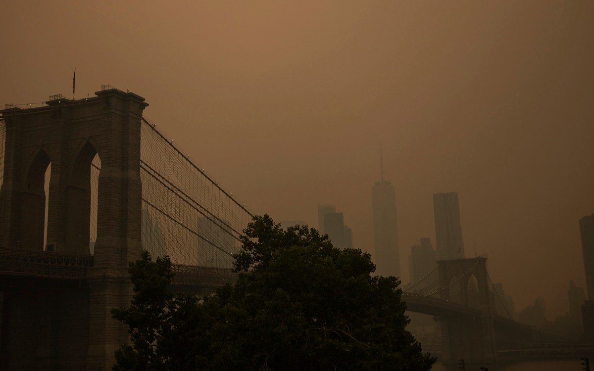 Orange haze over Brooklyn Bridge and New York City skyline.