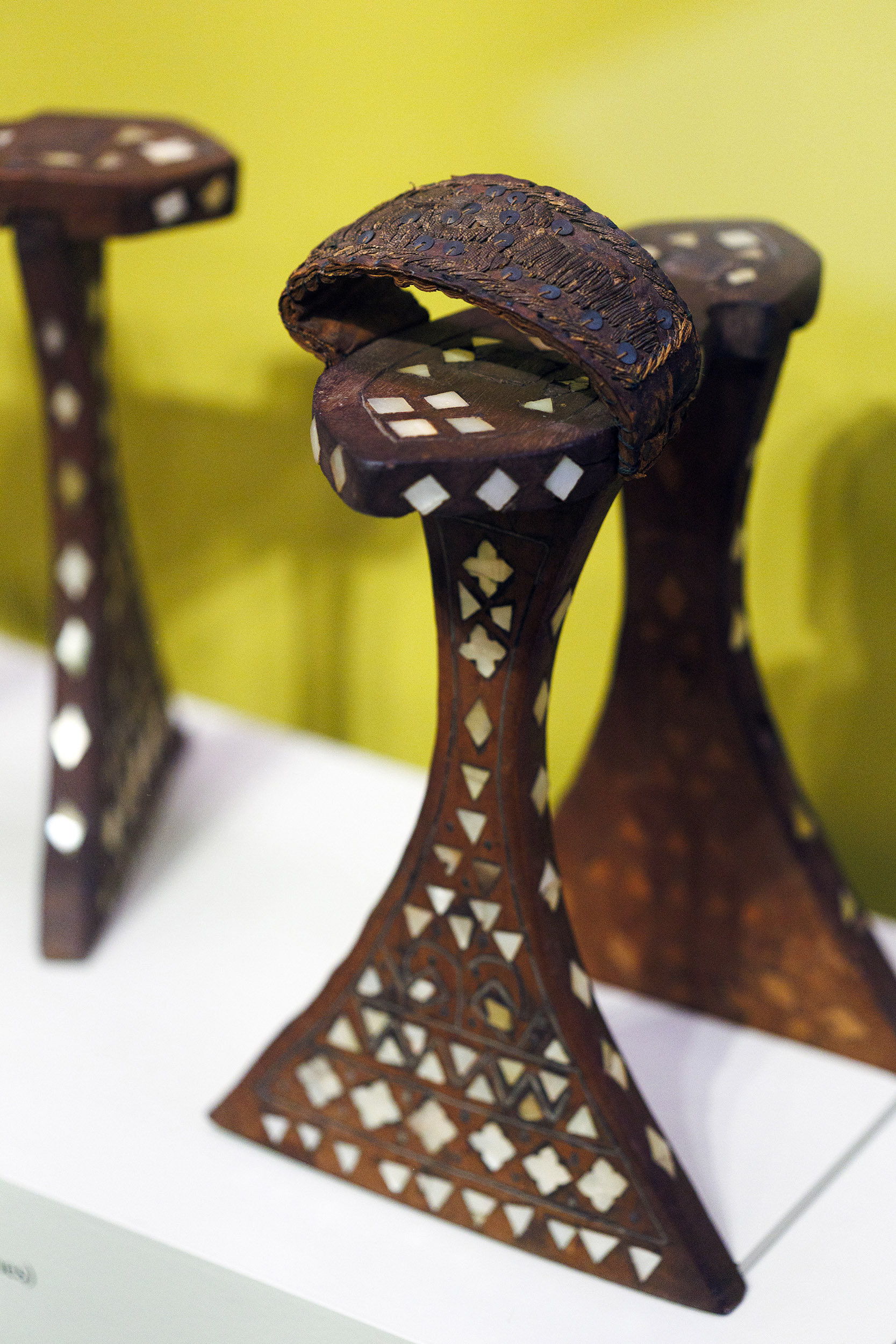 Tall carved wooden platform sandals inlaid with white glass and shell. 