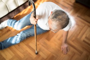 Older man with cane has fallen on the floor.