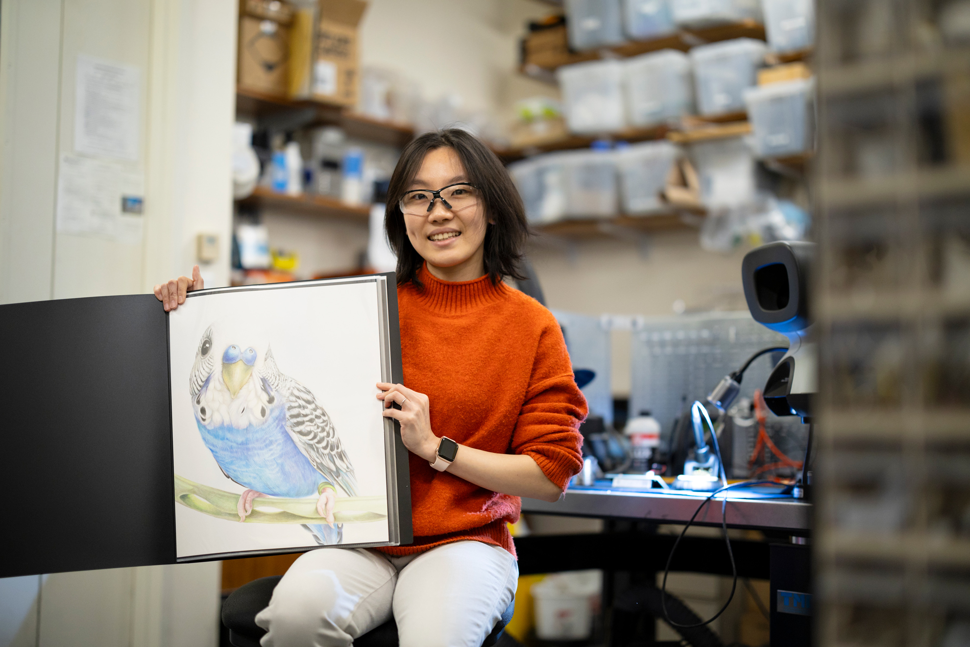 Yuwei Li, Neurotechnology Engineer at the Center for Brain Science and drawer, is pictured with her drawing of her pet, Lou, who is a budgie bird native to Australia.