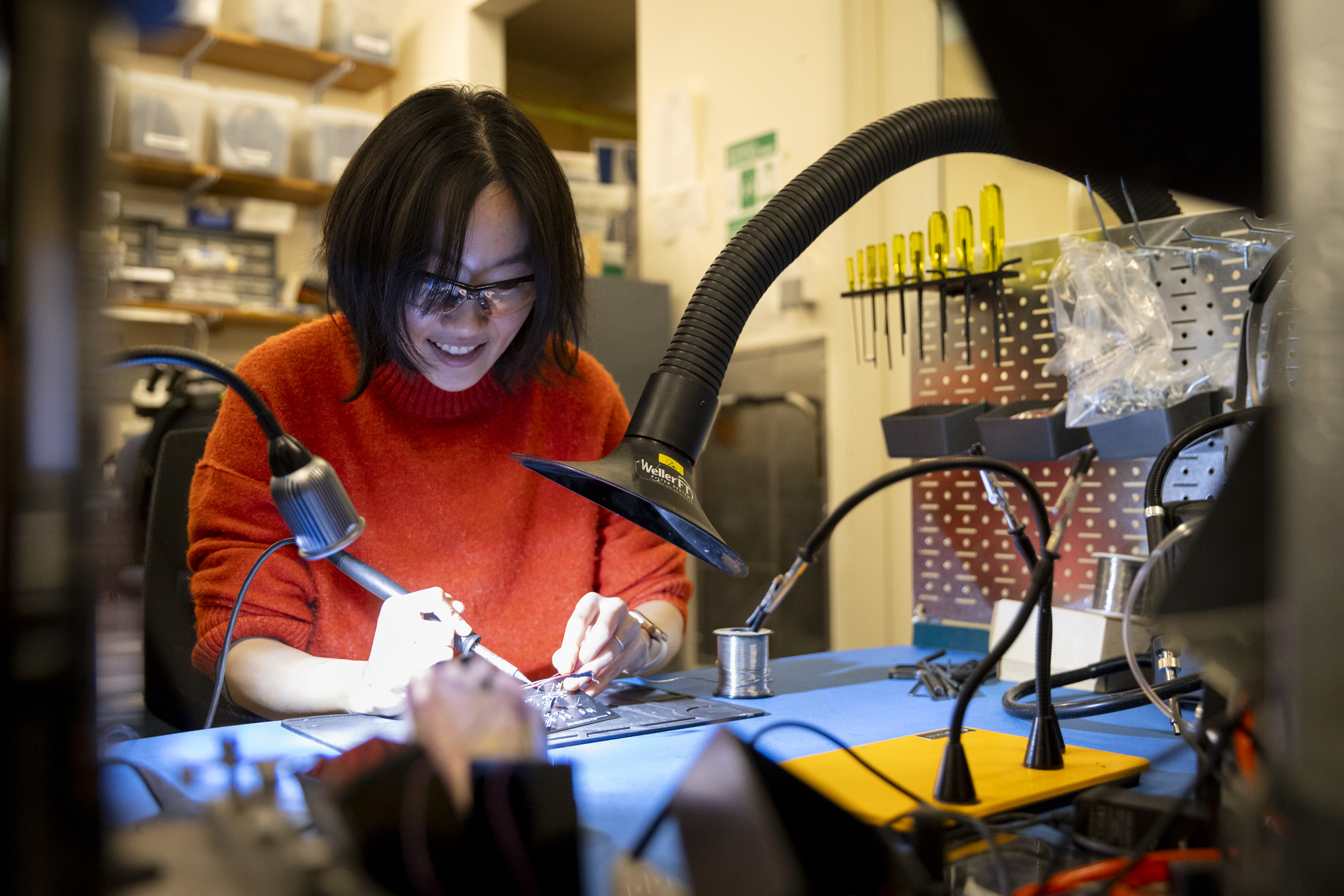 Yuwei Li, Neurotechnology Engineer at the Center for Brain Science and drawer, solders while working on a project for her job.