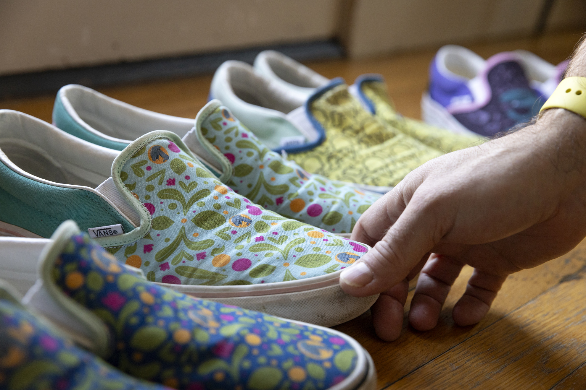Scott Murry, Digital Illustrator and Senior Designer at the Harvard Library, arranges pairs of custom Vans shoes that he has printed his designs on.