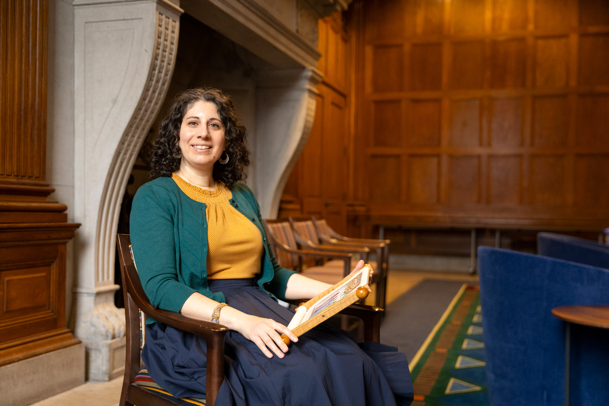 Veronica Bagnole (pictured), Digital Project Manager for the Harvard Graduate School of Design and embroiderer, posing for photos with her embroidery in the Thompson Room of the Barker Center.