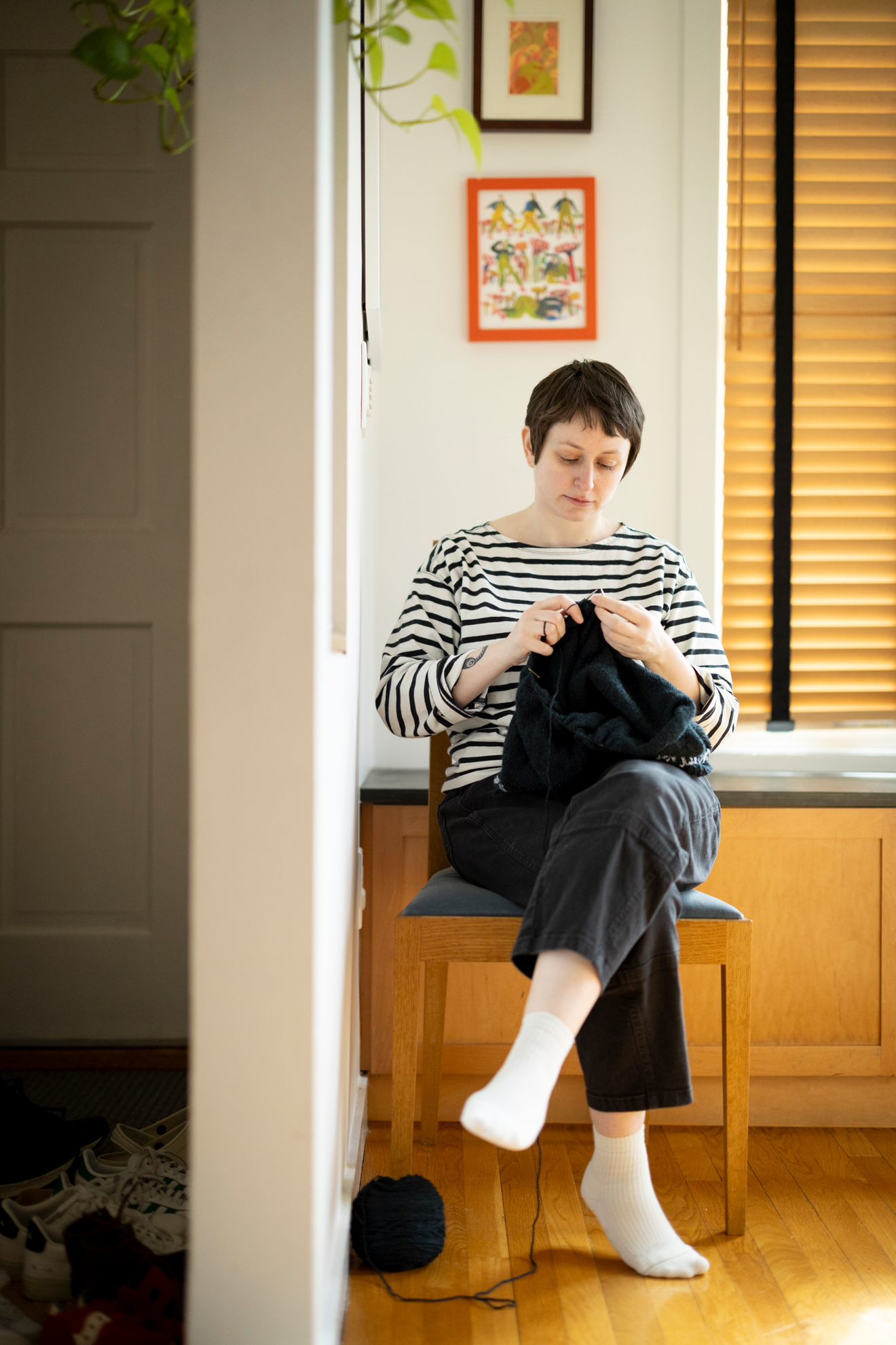 Eve Radovsky, Faculty Assistant at Harvard Law School, woodworker, and crafter is photographed knitting while sitting in a chair that she made.