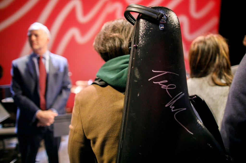A musician carries a freshly signed music case by Ted Nash following the concert.