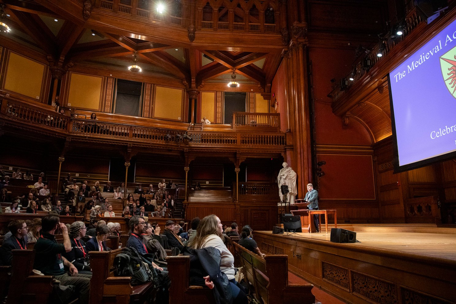 Sean Gilsdorf speaking in front of Sanders Theatre audience.