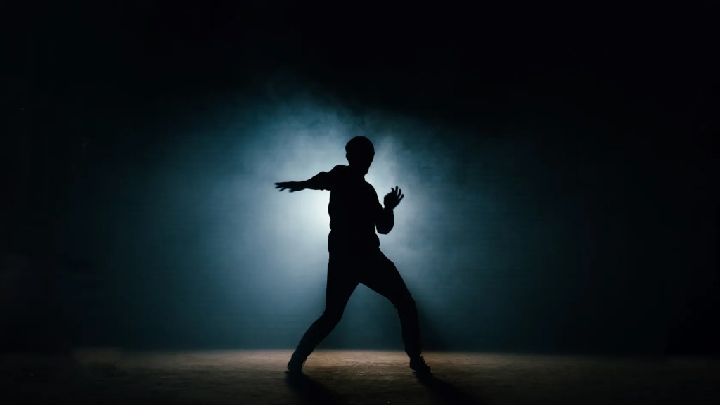 A dancer is silhouetted against a dark background.