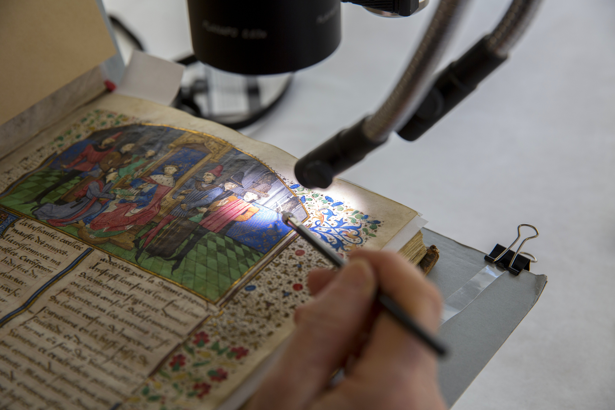 Book Conservator Catherine Badot-Costello uses a microscope to work on an illuminated, bound parchment manuscript from Houghton Library, dated 1464.
