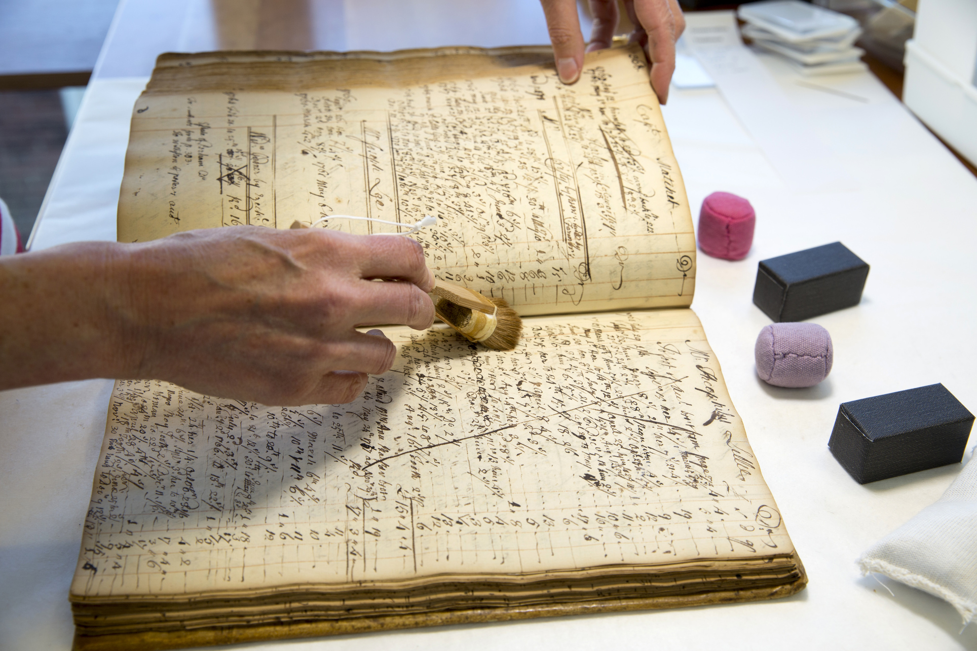 Anne Corrsin, Conservation Technician for Special Collections, cleans off an account book for medical services rendered by John Perkins (1698-1781) dating 1744 to 1780. B MS b64. Boston Medical Library, Francis A. Countway Library of Medicine, Boston, Mass.