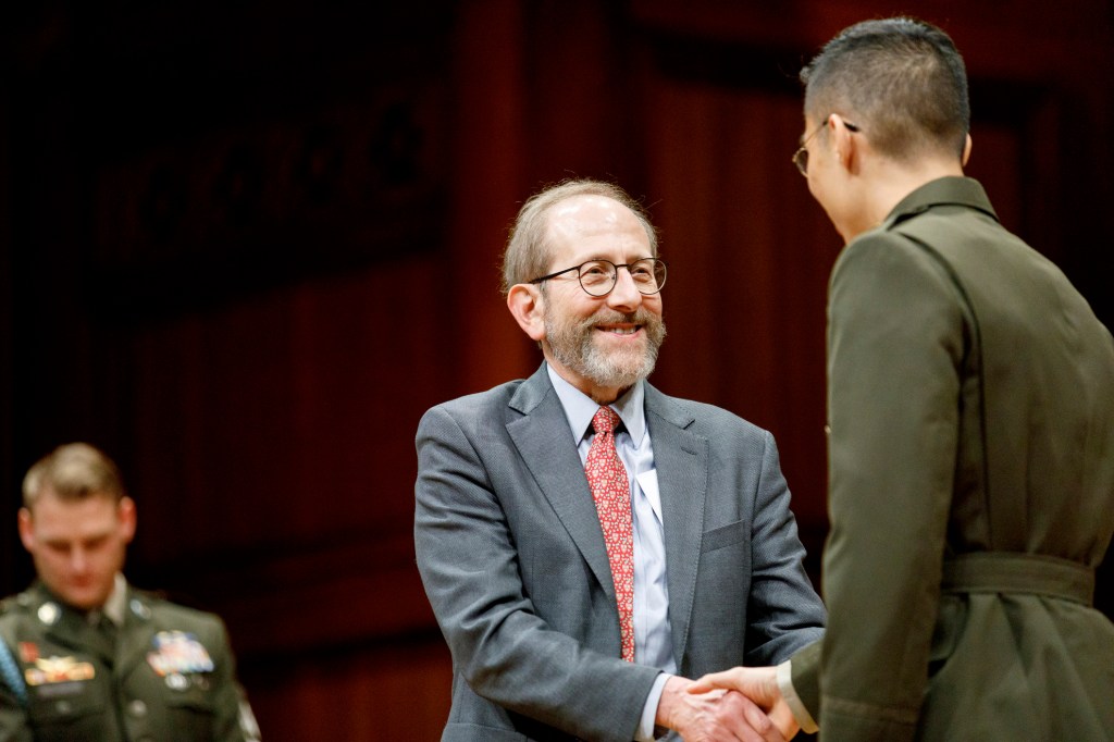 Harvard president Alan Garber shakes hands with Andrew Lim. 