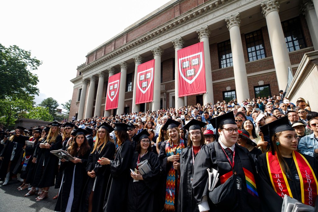 Graduates pose in front of Widener Library.